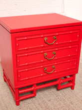 Load image into Gallery viewer, Image 13 of 21: A bright red three-drawer nightstand with a bamboo-inspired frame design and brass metal drawer pulls, shown against a white brick wall and beige carpet.
