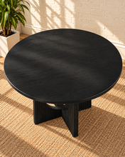Load image into Gallery viewer, Sylvia round dining table in Charcoal with black oak veneer finish, fluted pedestal base, and distinctive circular cutouts.

