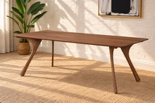 Load image into Gallery viewer, Tanner dining table in Natural Walnut with elongated rectangular top and sculpted splayed legs in a Mid-Century Modern design.

