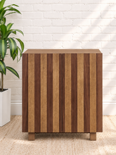 Load image into Gallery viewer, Veda warm oak bar cabinet with alternating vertical oak and walnut veneer striped doors and raised wood legs
