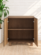 Load image into Gallery viewer, Veda warm oak bar cabinet with alternating vertical oak and walnut veneer striped doors and raised wood legs
