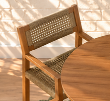 Load image into Gallery viewer, Victoria warm teak outdoor dining set with round slatted pedestal table and four woven faux rattan armchairs
