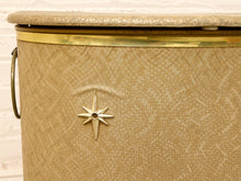 Load image into Gallery viewer, Vintage beige Atomic Age clothes hamper with rounded lid, brass-tone trim, textured patterned finish, and metal starburst accent
