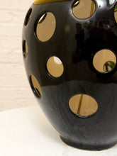 Load image into Gallery viewer, A glossy black ceramic vase with large circular cutouts, shown close-up against a light neutral background.
