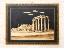 Load image into Gallery viewer, A framed artwork depicting ancient Greek or Roman ruins with tall columns under a dark sky with clouds, mounted on a white textured wall.
