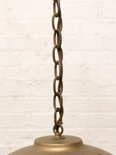 Load image into Gallery viewer, Close-up of a hanging pendant light fixture showing a weathered bronze metal chain and top cap against a white brick wall background.
