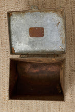 Load image into Gallery viewer, An open vintage metal storage box with a weathered silver-gray lid and a dark brown rusted interior, placed on a textured beige woven fabric background.
