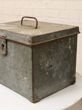 Load image into Gallery viewer, A vintage galvanized metal storage box with a handle and latch, displayed on a white pedestal against a white brick wall.
