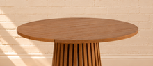 Load image into Gallery viewer, Vivian 31-inch round bar table in warm teak with slatted tabletop and tall sculptural vertical slat pedestal base
