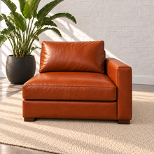 Load image into Gallery viewer, Image 7 of 14: Simulated Hollis 37-inch right-arm modular chair in Mont Blanc Caramel leather, with arm on the viewer's right and open left side, styled with a plain ivory rug and bird-of-paradise plant.
