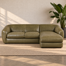 Load image into Gallery viewer, Image 1 of 8: Lucero olive-toned leather sectional with two sofa seats and a continuous right-facing chaise in a sunlit white-brick room.
