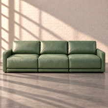 Load image into Gallery viewer, Image 1 of 18: Simulated Orinda three-piece sofa, front view in sage green Sequoia Rainforest leather, without accent pillows, in the Sunbeam white brick setting.
