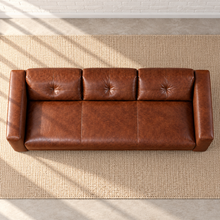 Load image into Gallery viewer, Image 3 of 6: Simulated overhead view of the Sullivan sofa in Crystal Ranch brown leather, showing the seat, three tufted back panels and straight padded arms on a beige woven rug.
