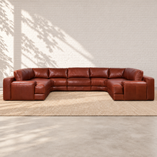 Load image into Gallery viewer, Image 1 of 5: Sunbeam Montara U-shaped modular sectional in Brighton Hero brown leather against a white brick wall with a neutral woven rug.
